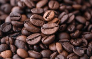 Close-up background of freshly roasted brown coffee beans filling the frame.